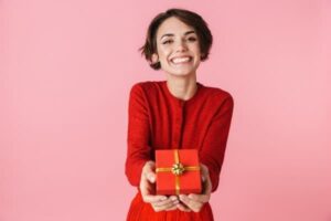 Woman holding gift and smiling, give back, clinical research